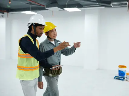 Two contractors in hard hats reviewing a space before a floor coating job